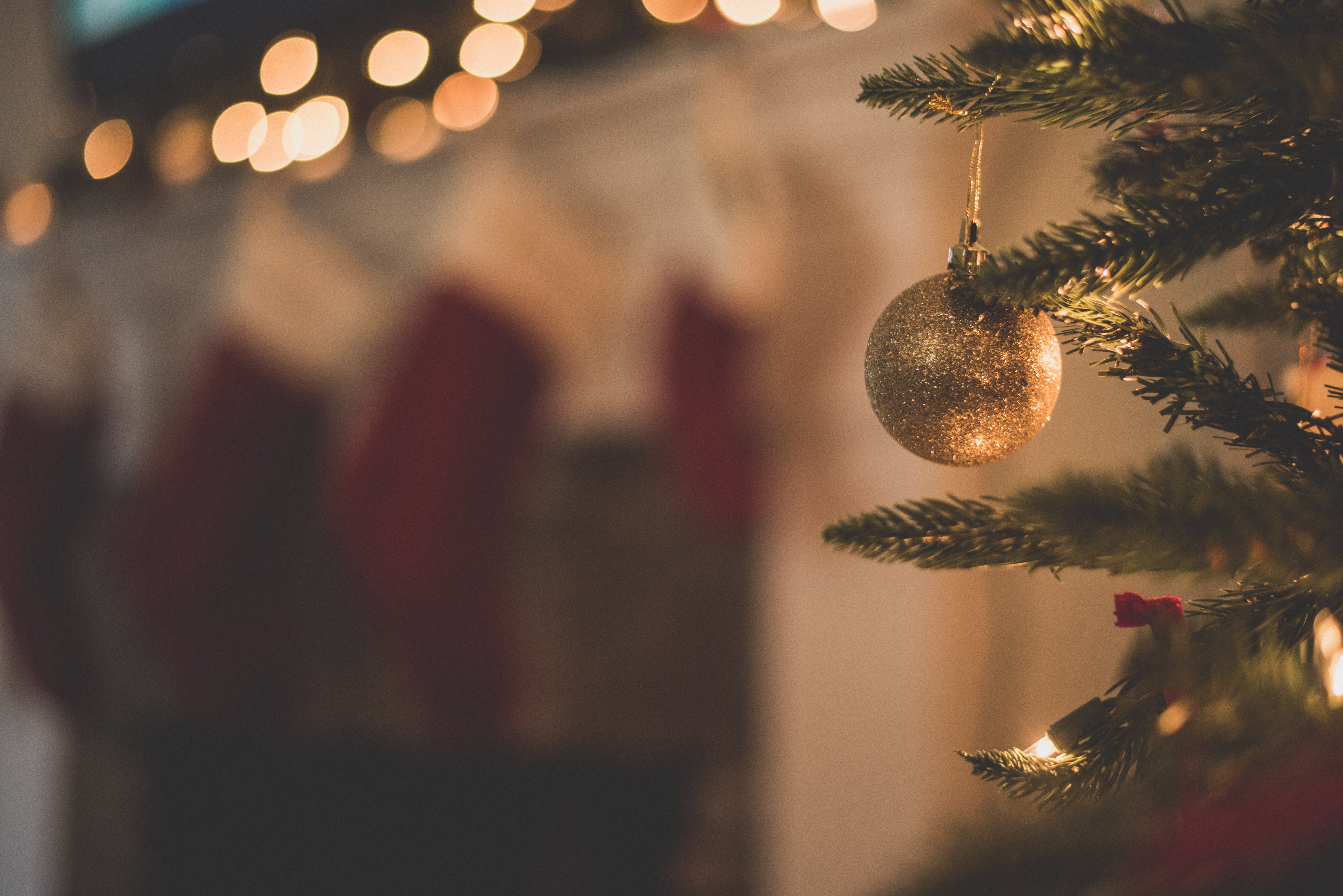 Fotot visar julstämning med inslag av gran, julkulor och röda nyanser i bakgrunden.